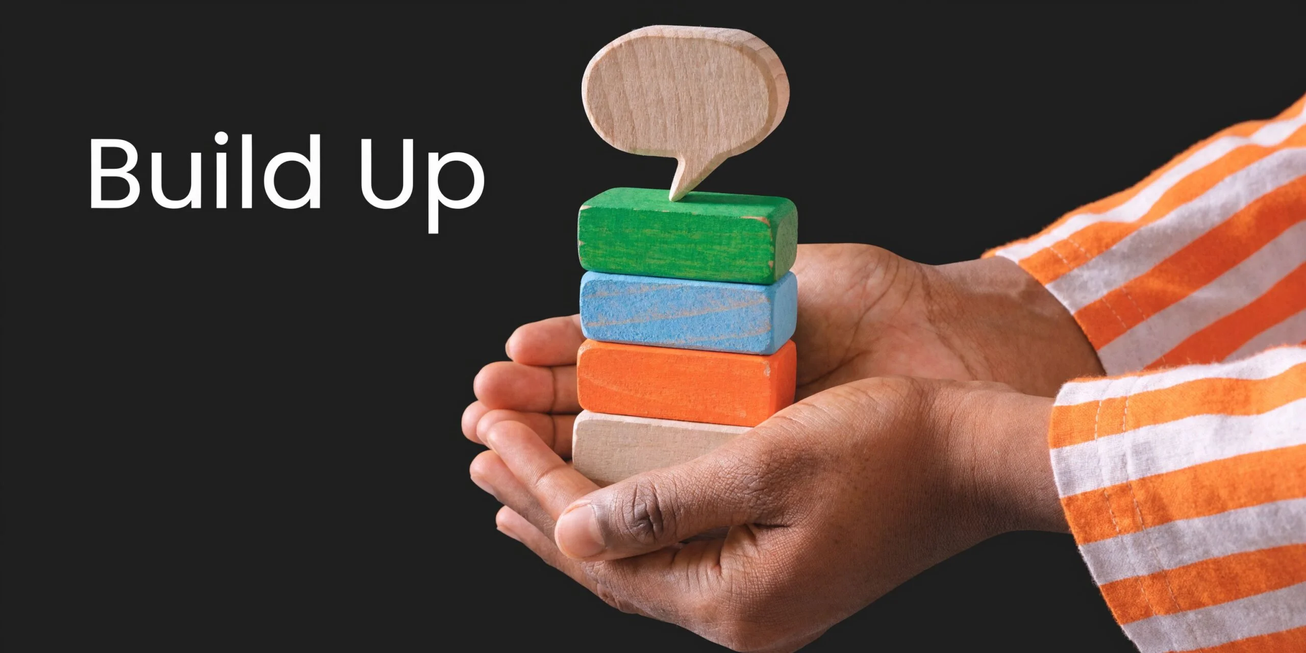 A person holding a stack of colorful wooden blocks with a wooden speech bubble icon on top.